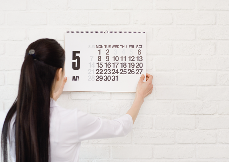 a woman hanging up a wall calendar