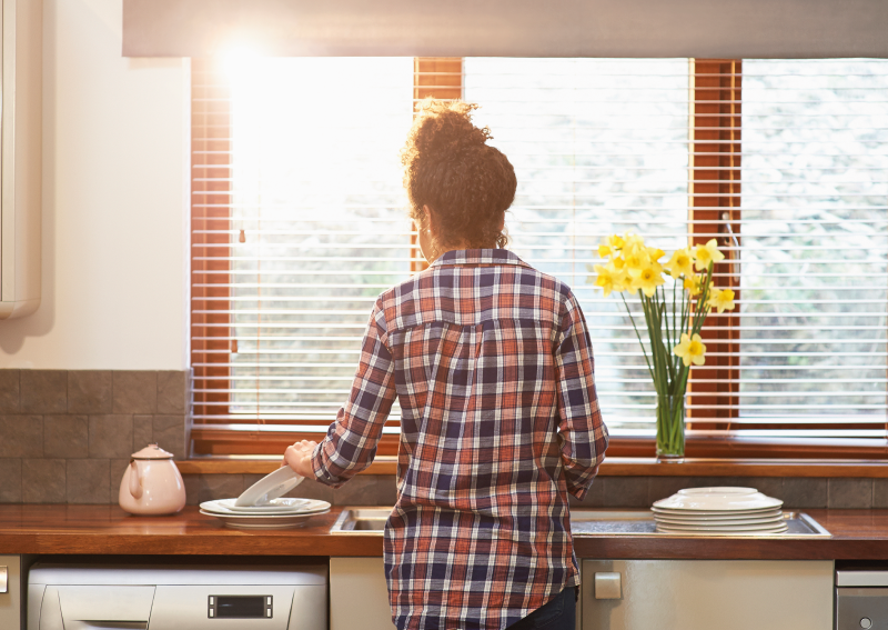 Woman at a window with blinds