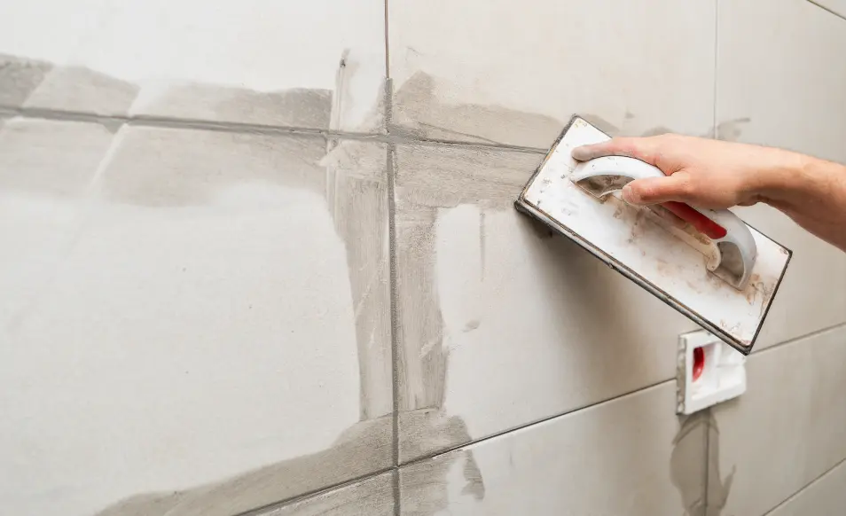 Grout paste being carefully applied on an area of tiling with the usage of a trowel.