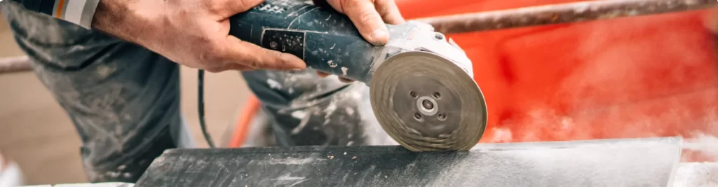 A professional traits man sawing a tile with an electronic circular saw on a stable position.